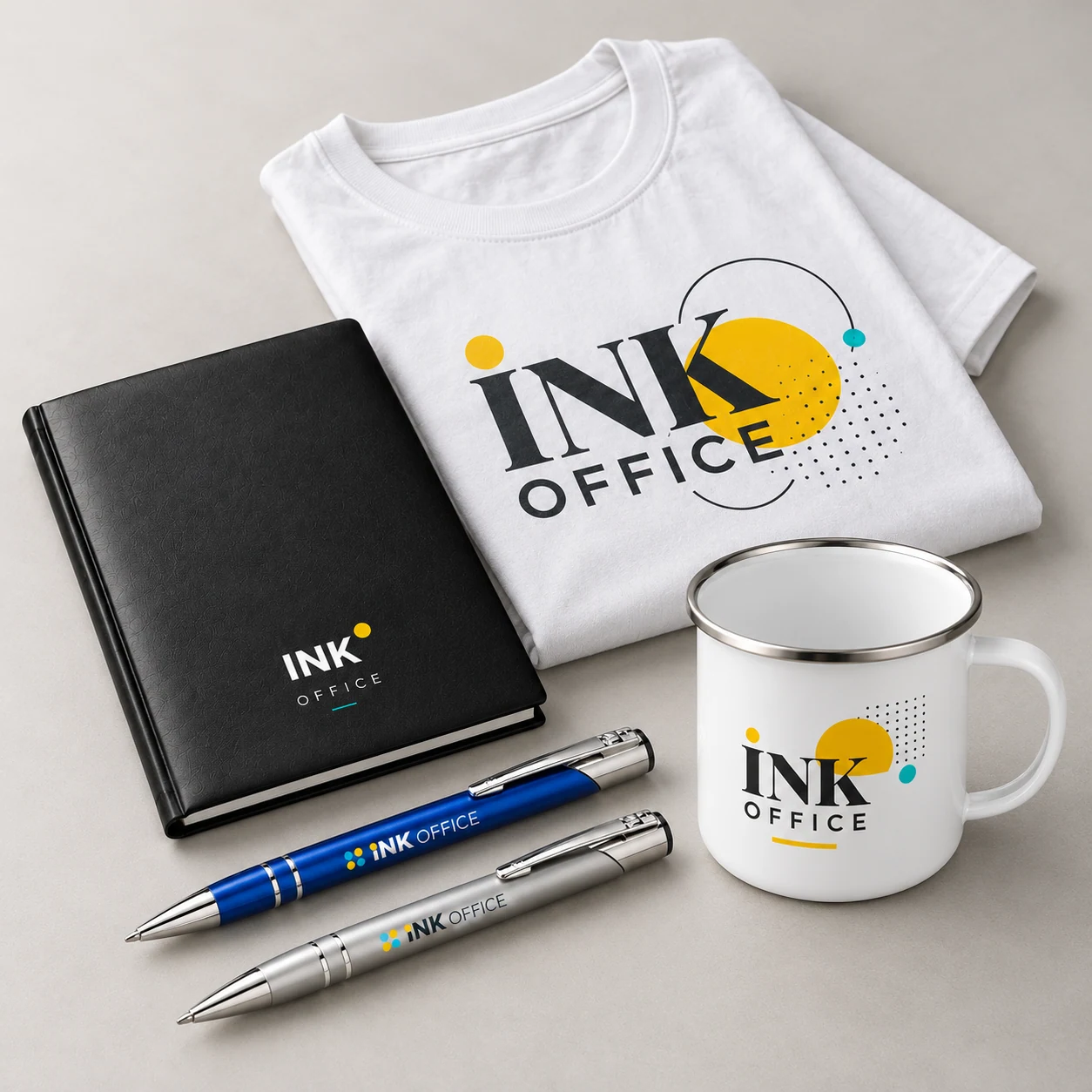 Simulare cu o agendă neagră, două pixuri metalice, o cană emailată albă și un tricou alb, personalizate Ink Office